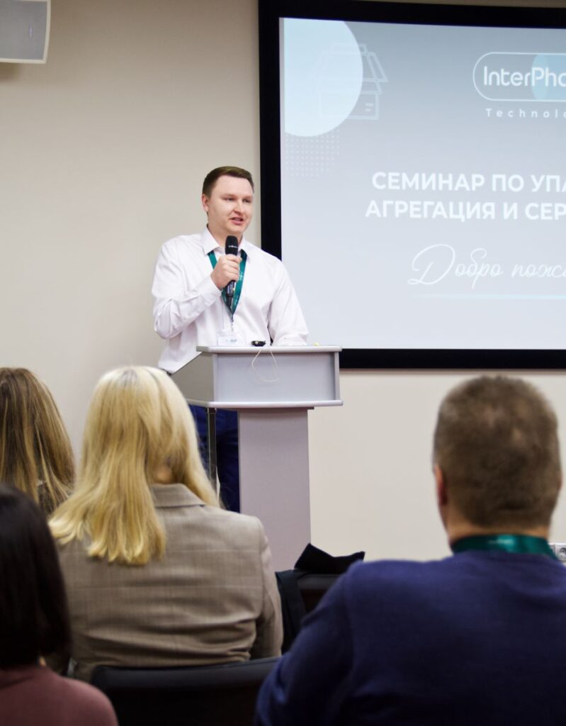 Константин Ткаченко выступает на семинаре за трибуной с микрофоном в руке и смотрит на слушателей